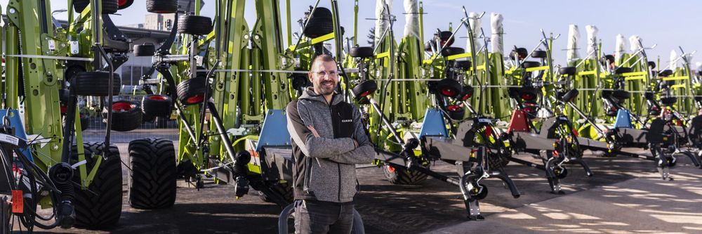 Marco Schwab standing among CLAAS agricultural machinery at the Bad Saulgau production facility