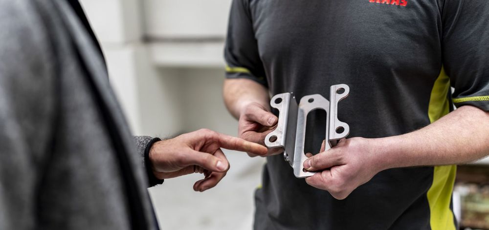CLAAS employees inspecting a precision bent metal component produced through automated bending